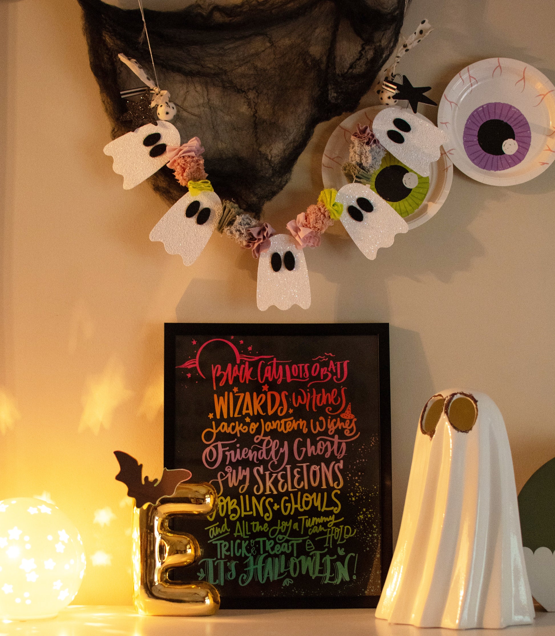 Halloween-themed decorations including ghost garlands, a framed text art piece, and a ghost figurine.
