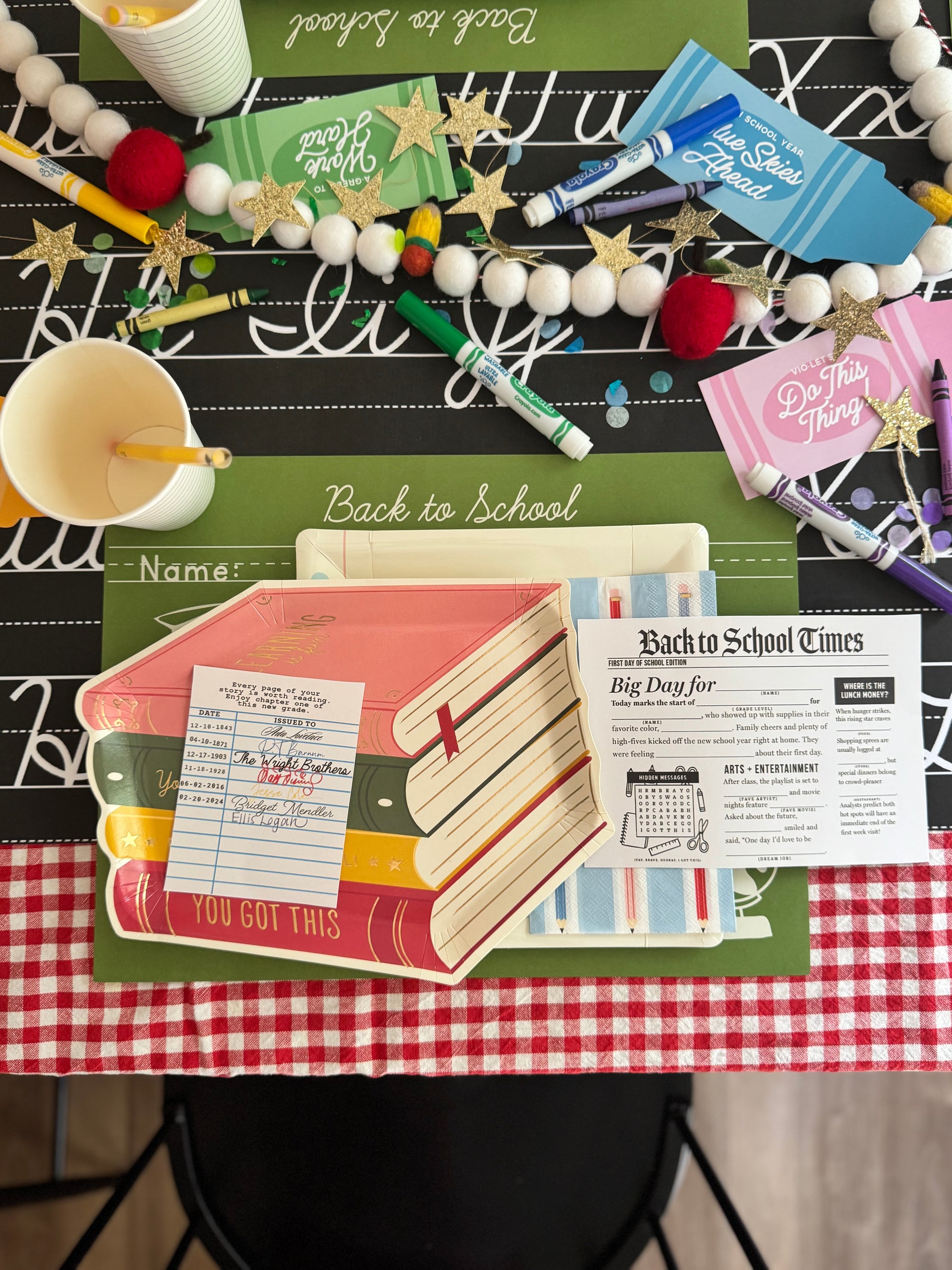 Back to school-themed table with stationery items on a checkered tablecloth.